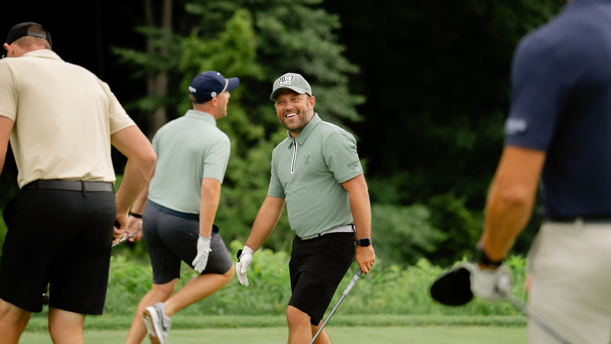 Group of golfers on a green course with trees in the background