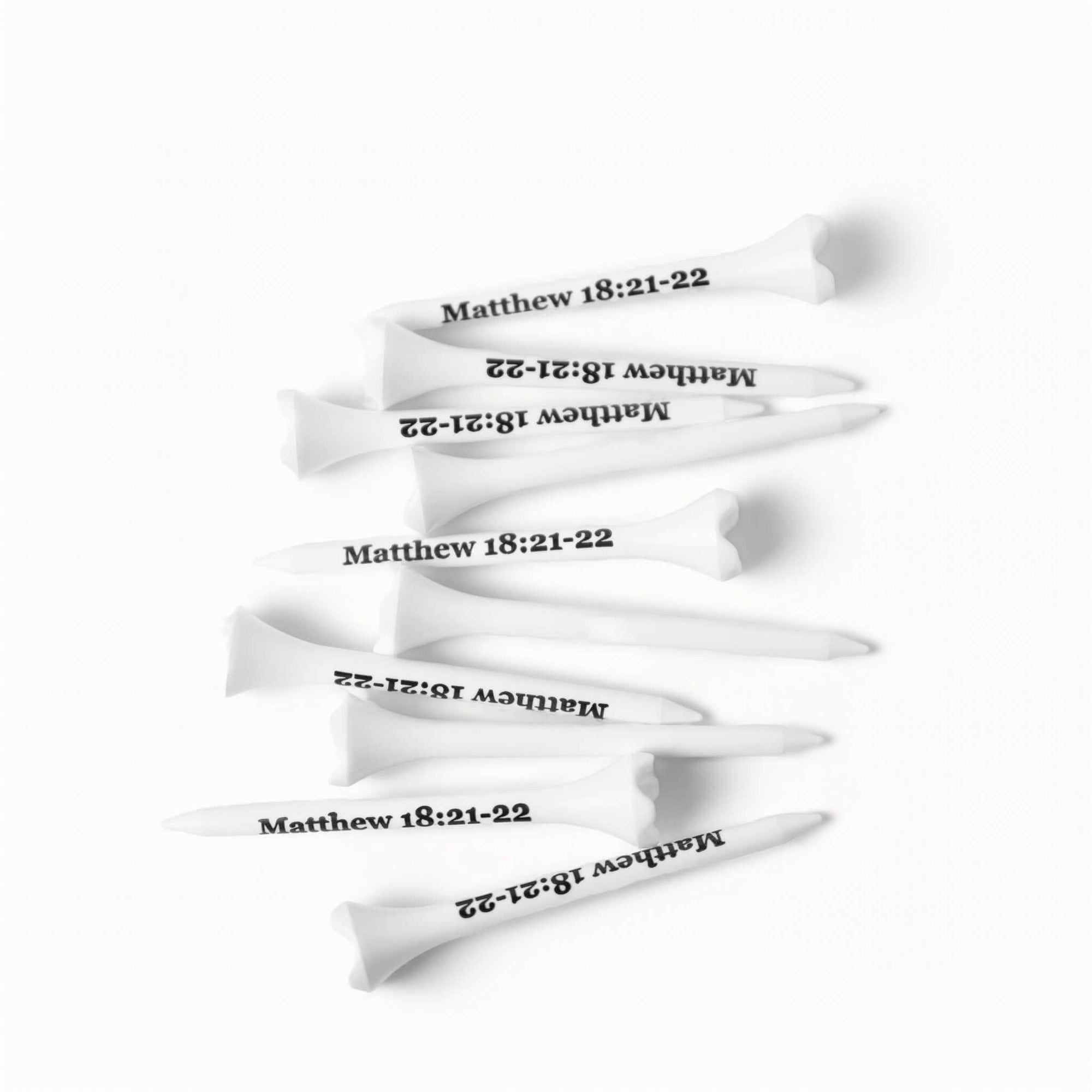 White plastic golf tees stamped with "Matthew 18:21–22" in black lettering, arranged diagonally on a white background – The Matthew Tee by 70x7 Golf Co.