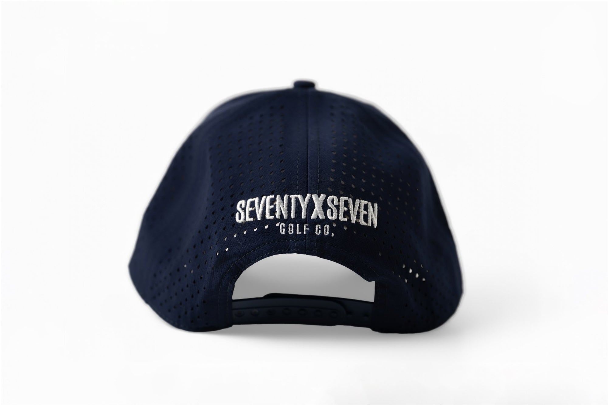 Back view of navy perforated snapback hat with white embroidered SEVENTYXSEVEN GOLF CO. logo and adjustable closure – The Quiet Lead Lid by 70x7 Golf Co.